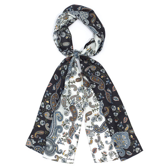 A two tone black and white scarf with multicoloured blue and yellow paisley print is pictured tied in a loop.