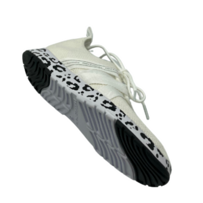 A bottom angle view of a white sneaker with a leopard print sole.