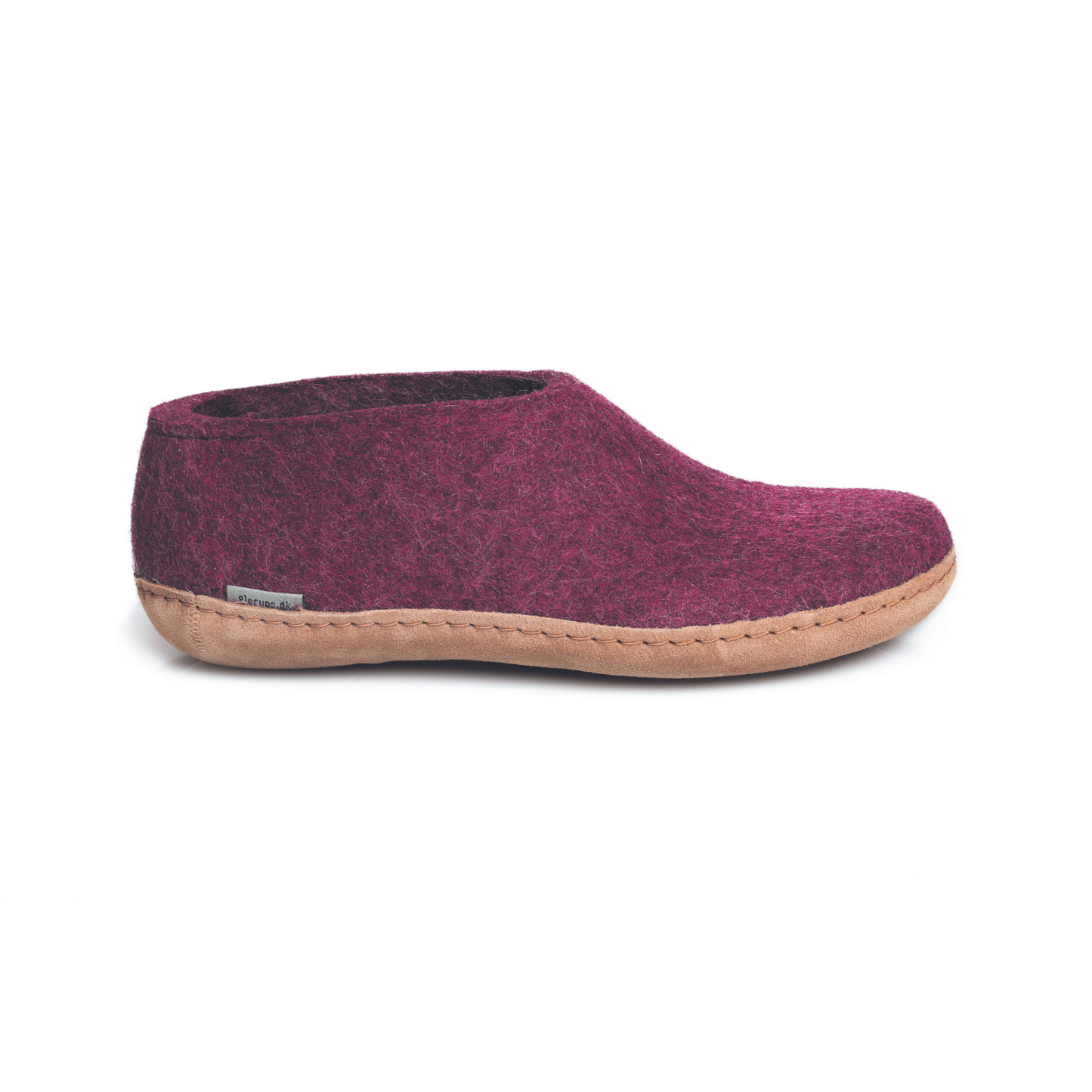 A dark-mauve slipper is pictured in profile, showing the high back of the heel. The bottom lined in tan leather has a small tag with the brand name attached in the seam where the leather meets the felted wool.