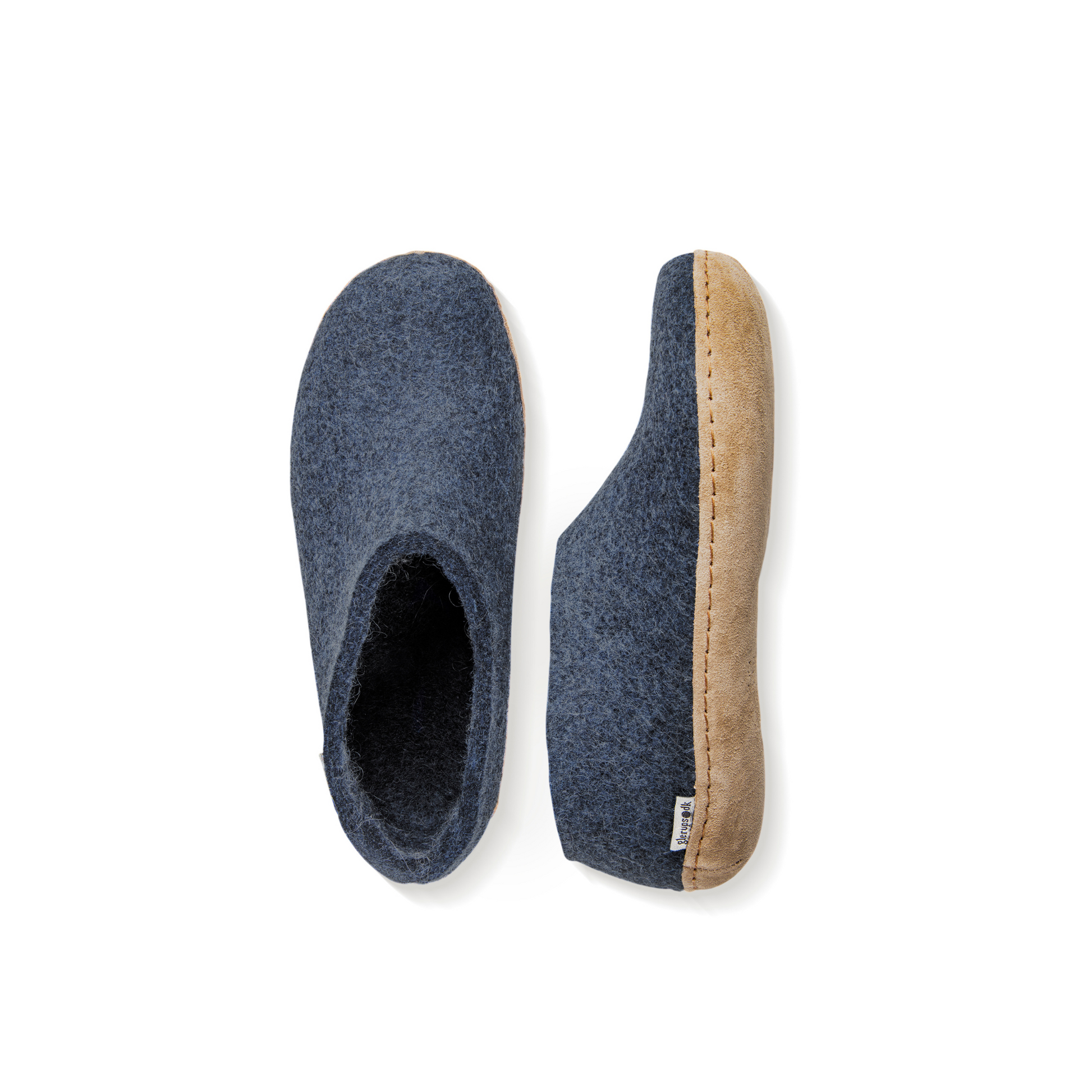 An overhead view of two dark denim blue felted wool tall-back slippers. One is pictured straight on, showing the top face of the slipper, while the other lays on its side, showing the profile with tan leather sole with a row of stitching.