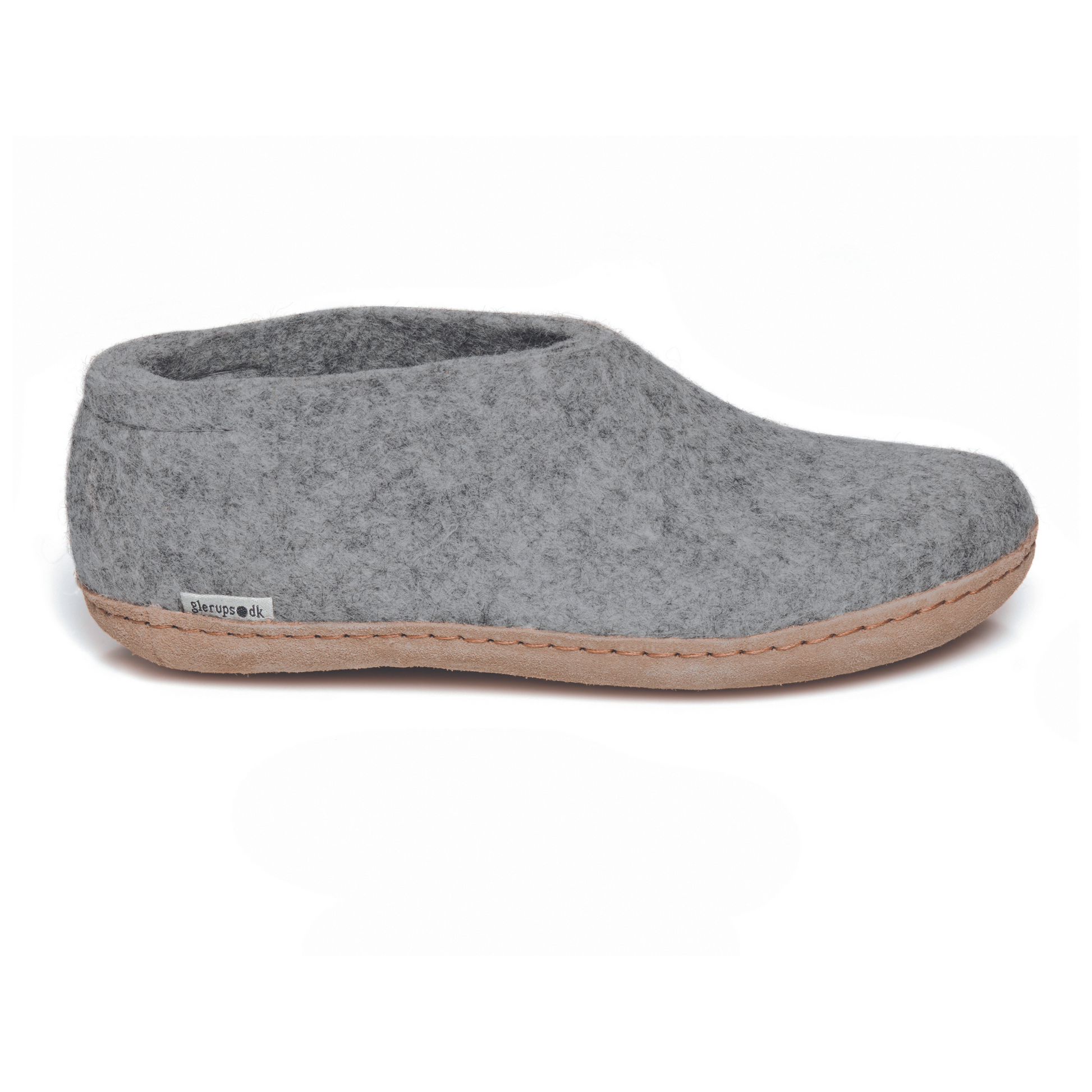A light grey slipper is pictured in profile, showing the high back of the heel. The bottom lined in tan leather has a small tag with the brand name attached in the seam where the leather meets the felted wool.