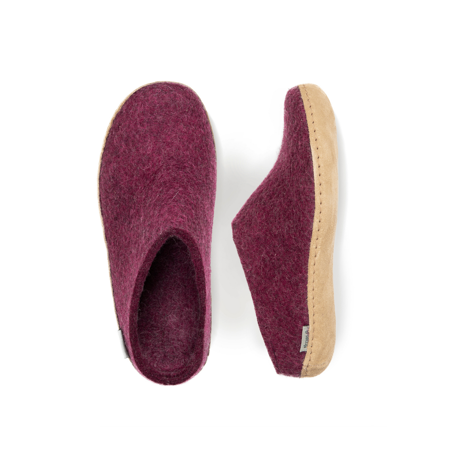 An overhead view of two deep-mauve felted wool slippers. One is pictured straight on, showing the top face of the slipper, while the other lays on its side, showing the profile with tan leather sole with a row of stitching.