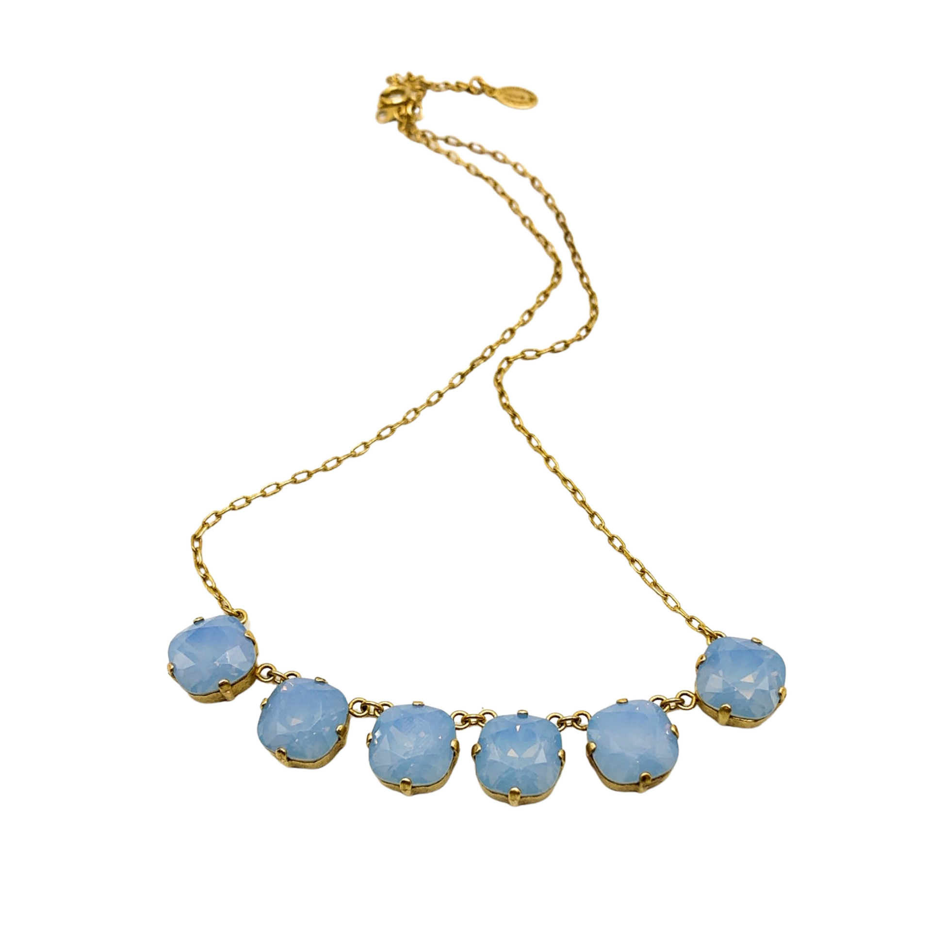 A top-down view of a necklace with a thin, clasped gold chain and six light blue, translucent crystals.
