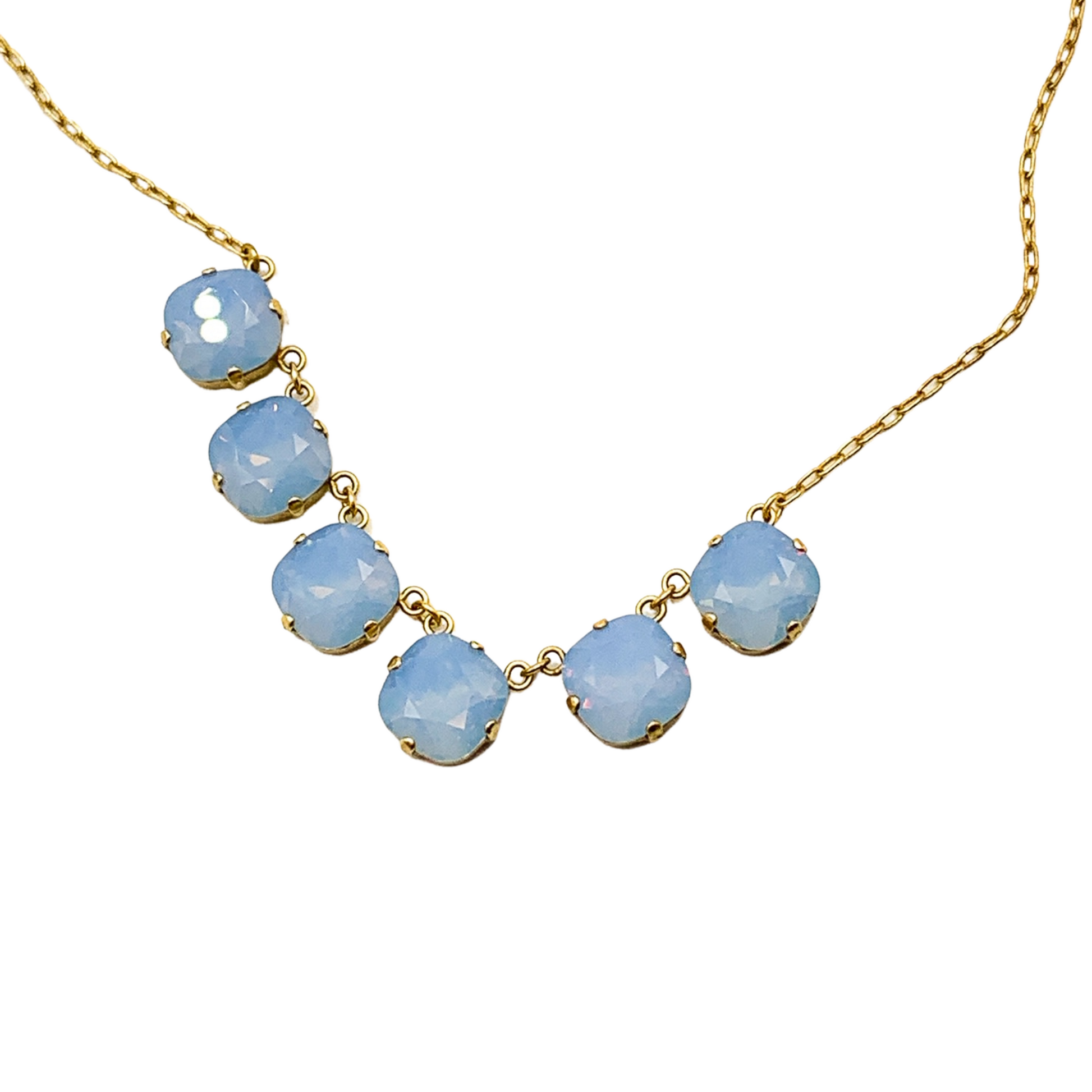 A closeup view of six light blue, translucent crystals on a gold chain.