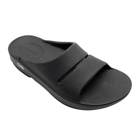 A right angle view of a black foam slide with two over-foot straps and a grippy sole.