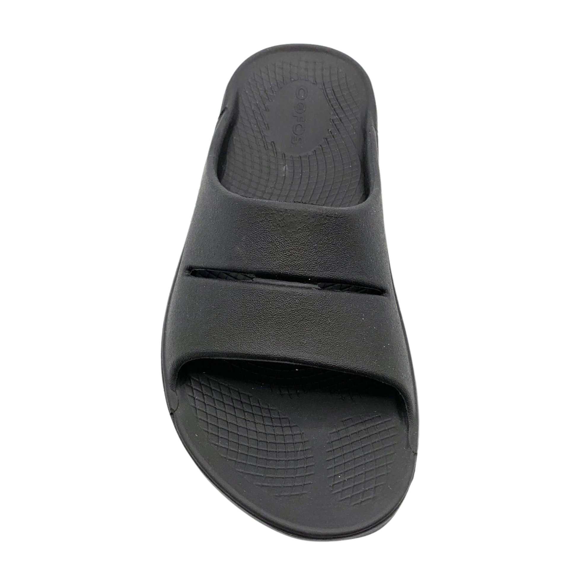 A top view of a black foam slide with two over-foot straps and a grippy sole.