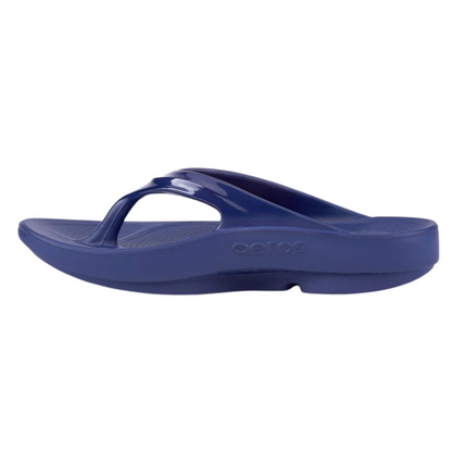 A left angle view of a navy foam sandal with a single between-toe strap and grippy sole.