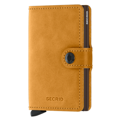A honey yellow suede wallet is pictured with black metallic inner cardholder and a button closure.