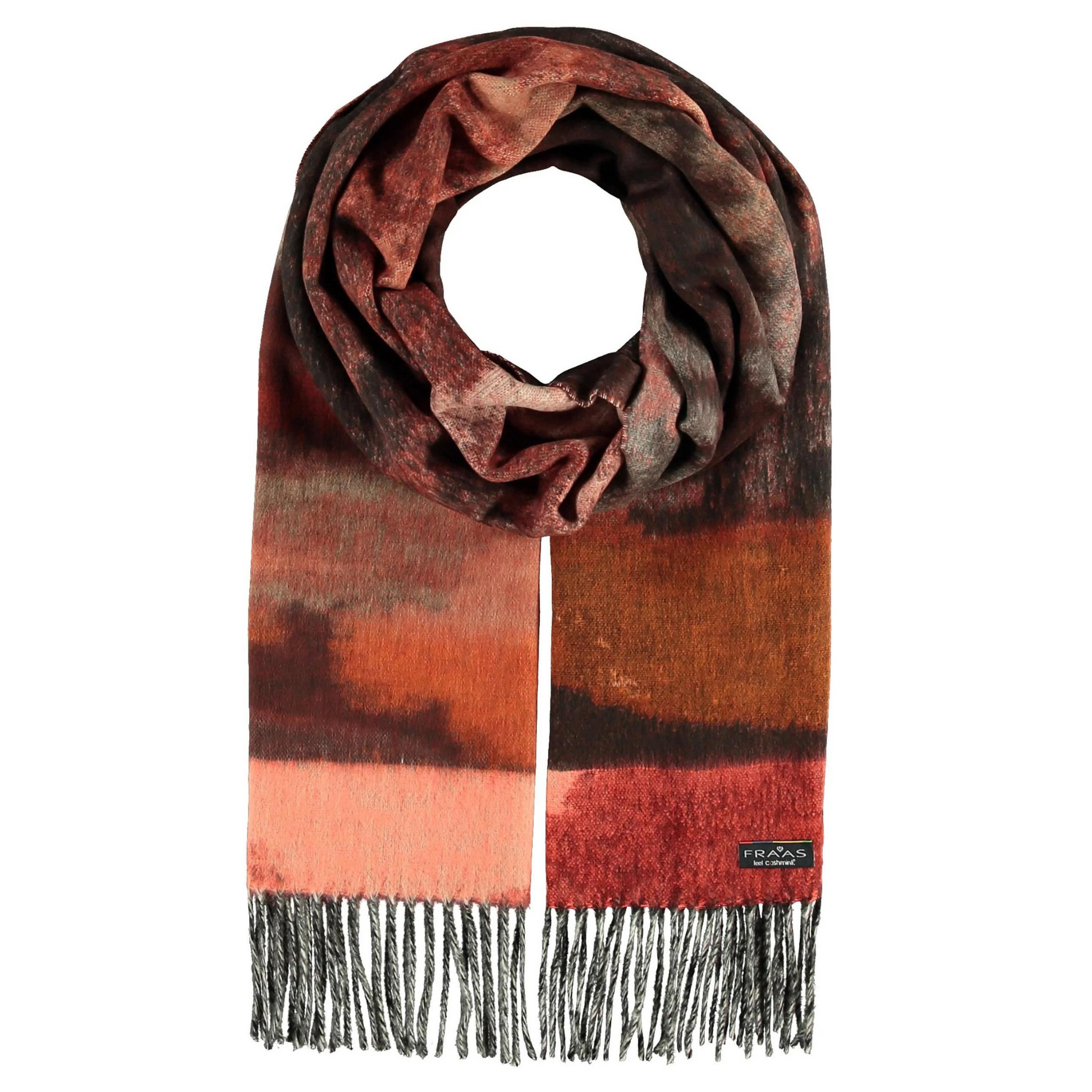 A tonal red and brown scarf is tied, showing a tapestry like print with tassels at the end.