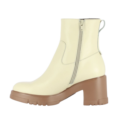 A left side view of a cream coloured leather boot with a caramel coloured outsole.